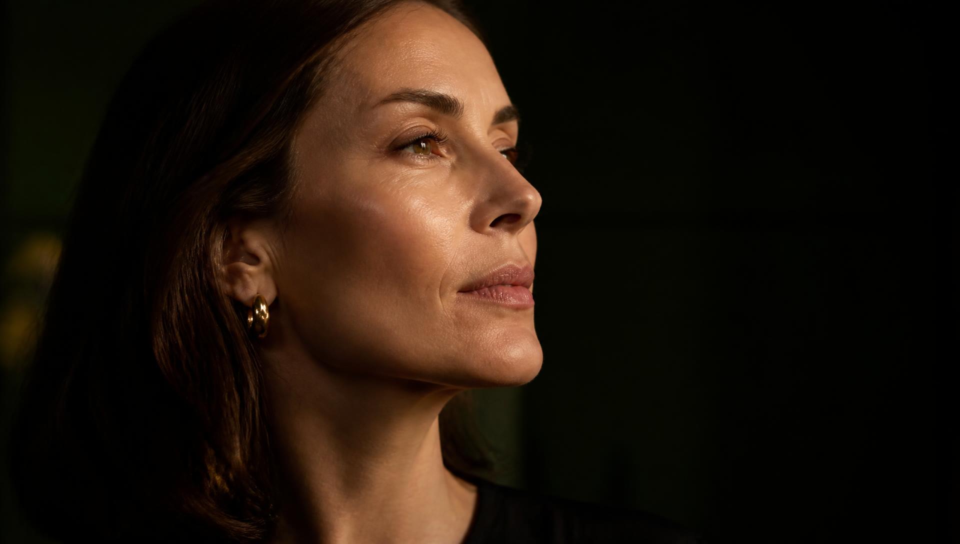 Editorial profile of a woman's jawline and neck in warm, low light